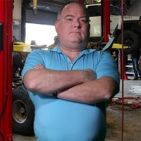 Gus Whitwill Husky balding man with arms folded across his chest